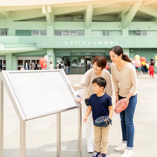 球場正面広場で家族連れが試合日の案内板を確認する様子